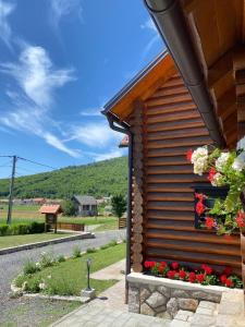 una cabaña de madera con flores a un lado. en Ruralna kuća za odmor Marta, en Otočac