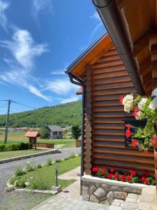 a log cabin with flowers on the side of it at Kuća za odmor Marta in Otočac