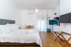 a bedroom with a white bed and a kitchen at Mar- Milfontes Rentals in Vila Nova de Milfontes
