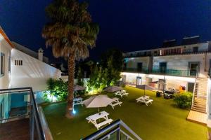 an outdoor patio with umbrellas and a palm tree at night at Mar- Milfontes Rentals in Vila Nova de Milfontes