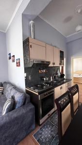 a kitchen with a stove top oven next to a couch at Priam Garden in Durrës