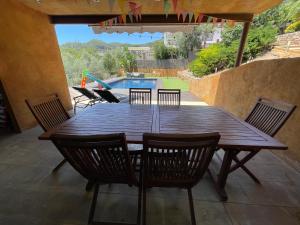 einen Holztisch und Stühle auf einer Terrasse mit einem Pool in der Unterkunft Casa con piscina y vistas en Vallirana/Barcelona in Vallirana