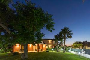 uma casa com relva e palmeiras à noite em Villa Seaside - Beach Retreat with jacuzzi em Siracusa