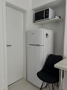 eine Küche mit einem weißen Kühlschrank und einem schwarzen Stuhl in der Unterkunft Secret Place Apartment in Stari Grad