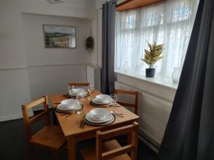 a wooden table with plates and wine glasses on it at 3 bedroom house in Grays Thurrock