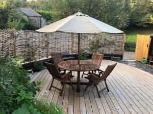 a table and chairs with an umbrella on a deck at Riverside Retreat in Totnes