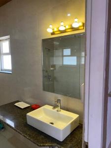 a bathroom with a white sink and a mirror at Charming 2 Bedroom Rustic Villa with Garden in Lansdowne
