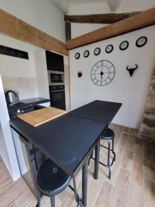 una mesa negra en una cocina con un reloj en la pared en Studio de charme - Le Céleste, en Vergèze