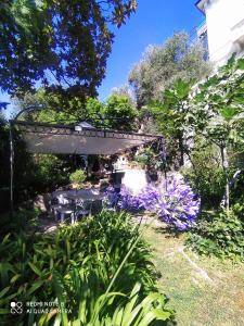 a garden with a picnic table and purple flowers at Pergolato suite in Sanremo