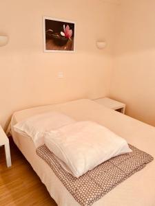 uma cama num pequeno quarto com uma flor rosa na parede em Vacances à la Mer la Turballe Ajonc em La Turballe