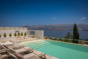 a swimming pool with chairs and a view of the water at Villa Lavanta - Iris sunset villas in Lépedha