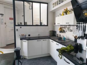 a kitchen with white cabinets and black counter tops at Maison sur le quai in La Rochelle