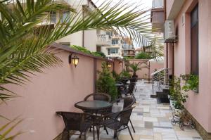 an outdoor patio with tables and chairs and palm trees at Kalina Family Hotel in Burgas