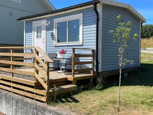 a tiny house with a deck and a table at Cozy cottage stay in Falkenberg