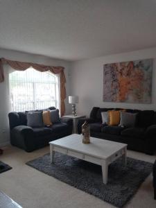 uma sala de estar com dois sofás e uma mesa de centro em Amore's luxurious 4 bedroom home. em Kissimmee