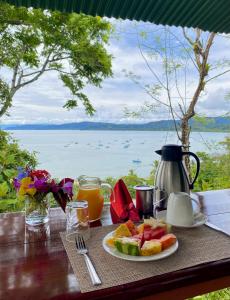 a table with a plate of fruit and a view of the water at Casa Horizontes Corcovado in Drake