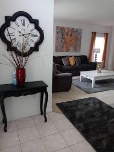 sala de estar con reloj en la pared en Amore's luxurious 4 bedroom home. en Kissimmee