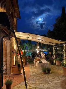 eine Terrasse mit Tischen und einem weißen Regenschirm in der Nacht in der Unterkunft casaluna in Suvereto