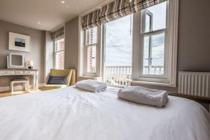 um quarto com uma grande cama branca e janelas em Swn-y-Don em Aldeburgh