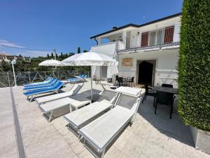 een groep ligstoelen en parasols op een patio bij Appartamenti Alice in Lazise