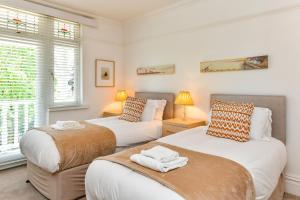 twee bedden in een kamer met twee ramen bij Just Stay Wales - Highmead House, Swansea 