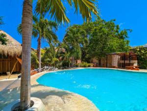 a swimming pool with a palm tree in a resort at Xhule Hotel Boutique in Tulum