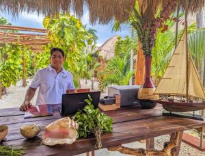 a man sitting at a table with a laptop at Xhule Hotel Boutique in Tulum