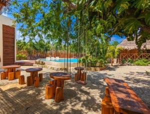 a group of wooden tables and benches in front of a pool at Xhule Hotel Boutique in Tulum