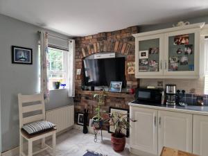 a kitchen with a tv on a brick wall at Tirquin House in Omagh