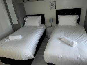 Duas camas num quarto com lençóis e almofadas brancos em Sunderland City Centre Modern 2 Bed Apartment em Sunderland