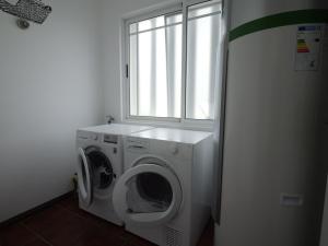 eine Waschküche mit einer Waschmaschine und einem Fenster in der Unterkunft Forte do Ilhéu de Vila Franca in Vila Franca do Campo