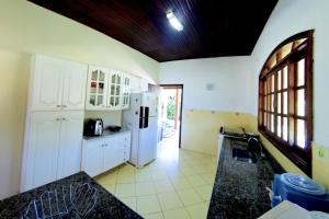 uma cozinha com armários brancos e um frigorífico branco em Chácara condomínio perto de SP em Ibiúna