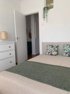 a white bedroom with two beds and a dresser at Apt 20 min from downtown train in Amadora