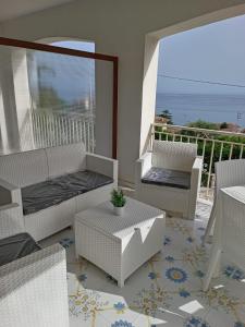 eine Terrasse mit Stühlen und Tischen sowie einen Balkon mit Meerblick in der Unterkunft L’Oasi del Barone in Villammare