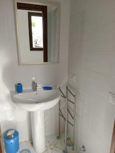 La salle de bains blanche est pourvue d'un lavabo et d'un miroir. dans l'établissement L’Oasi del Barone, à Villammare