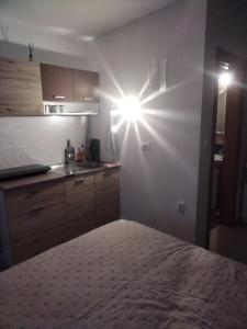 a room with a kitchen with a light on the wall at Studio apartman MIR in Kanjiža
