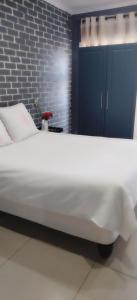 a large white bed in a room with a brick wall at Mels in Richards Bay