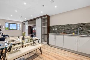 uma cozinha e sala de estar com uma mesa de vidro e cadeiras em 2 bed, 2 bath Gated Heathrow Lux Apartment em West Drayton