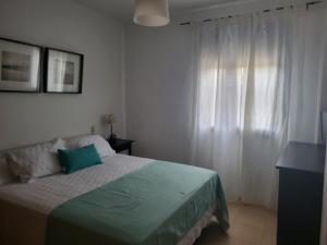 コニル・デ・ラ・フロンテーラにあるApartamento Con Jardin Y Piscinaのベッドルーム1室(ベッド1台付)、窓(白いカーテン付)