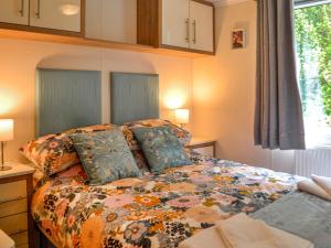 a bedroom with a bed with a colorful comforter and a window at Wildhaven Lodge in Dalbeattie