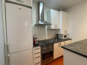 a kitchen with white cabinets and a stainless steel refrigerator at Piso en pleno centro de Madrid in Madrid