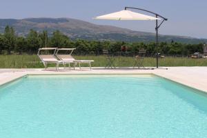 einen Pool mit einem Stuhl und einem Sonnenschirm in der Unterkunft LE CANONICHE NEL MATESE ALBERGO DIFFUSO in San Massimo