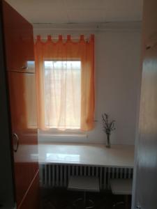 a window with an orange curtain in a kitchen at Apartman studio Oranž in Kladovo