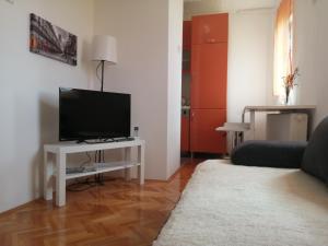 a living room with a television on a white table at Apartman studio Oranž in Kladovo