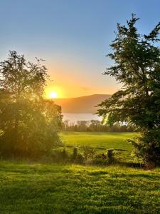 a sunset over a field with trees in the foreground at 1 Loch Ness Heights in Inverness +13 photos