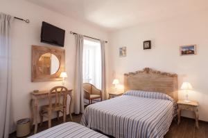 a bedroom with two beds and a tv on the wall at Hôtel de la Plage Les Arcades in Algajola