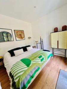 a bedroom with a bed with a green and white blanket at Lodge avec spa au coeur de Brocéliande in Beignon +24 photos
