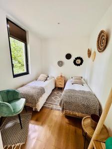 two beds in a room with a chair and a window at Lodge avec spa au coeur de Brocéliande in Beignon