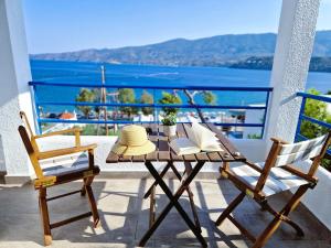 a table with a hat and two chairs on a balcony at Christine Studios in Poros