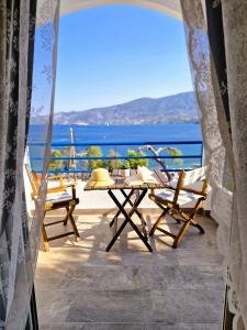 einen Tisch und Stühle auf einem Balkon mit Meerblick in der Unterkunft Christine Studios in Poros